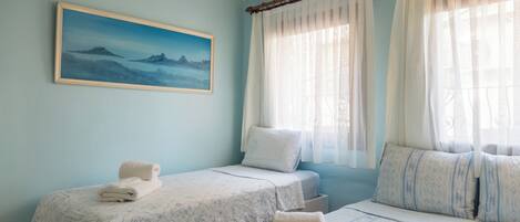 Une chambre d’hôtel avec deux lits, un tableau au mur et une fenêtre avec des rideaux.