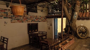 A rustic dining area with a brick wall, wooden furniture, and a hanging pot. - Tarihi Rum Konağı Antikhan (Ayvalik)