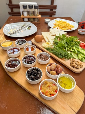 A wooden table with a variety of food items including bread, cheese, vegetables, and condiments. - Tarihi Rum Konağı Antikhan (Ayvalik)