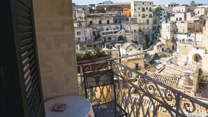 A balcony with a table and chairs, overlooking a densely packed urban area with historic buildings. - B&B Donna Lina (Matera)