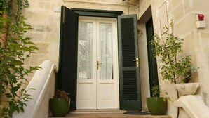 A stone building with a white door, green shutters, and a small balcony. - B&B Donna Lina (Matera)