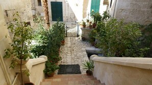 A narrow stone staircase leading to a door with a metal gate, surrounded by potted plants and a stone wall. - B&B Donna Lina (Matera)