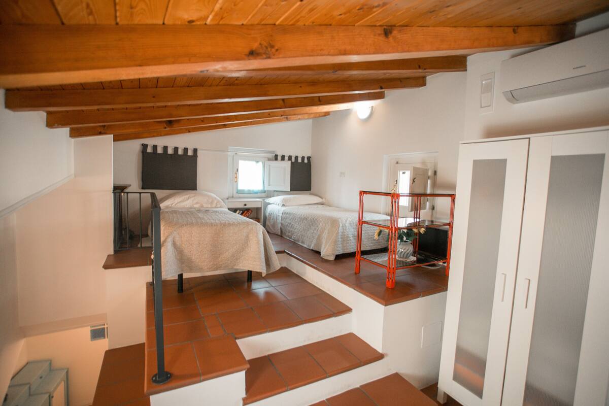 Un dormitorio con dos camas, un armario y una pequeña mesa con una silla.