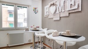 Una cocina moderna con electrodomésticos blancos, un ventanal con vistas a edificios y una pared con un letrero que dice 'HOME'.