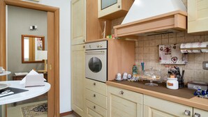 Una cocina compacta con horno integrado, un pequeño comedor y un espejo.