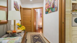 Un pasillo con puertas de madera, una mesa con una lámpara y un jarrón de flores.
