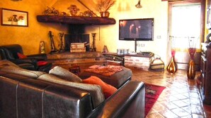 A cozy living room with a fireplace, leather sofa, and a television. - Azienda Agrituristica I Tre Casali (Magione)