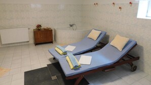 A room with two massage tables, a bathtub, a wooden cabinet, and a radiator. - Vila Arnau (Hostinne)