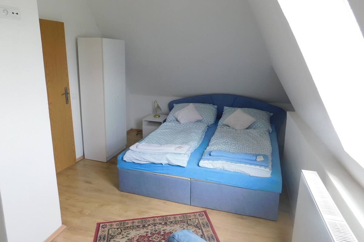 Un dormitorio con cama, mesita de noche, armario y radiador.