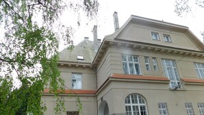 A two-story building with a stone foundation, multiple windows, and a red-tiled roof. - Vila Arnau (Hostinne)