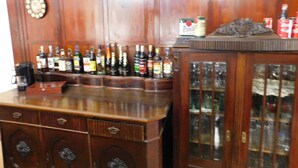 A wooden bar area with multiple liquor bottles, a coffee machine, and a clock on the wall. - Vila Arnau (Hostinne)