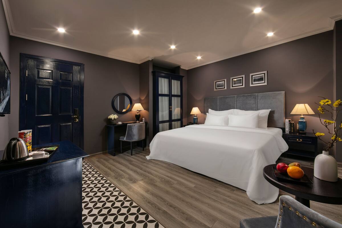 A modern hotel room with a large bed, bedside tables, a desk, and a chair.