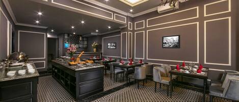A modern dining area with a central island, black and white patterned floor, and a chandelier.