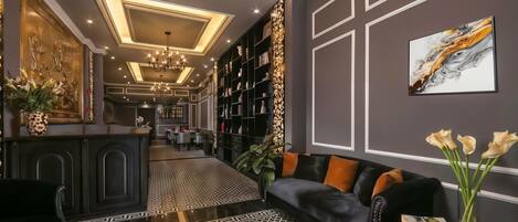 A modern interior with a black leather sofa, a dining area, and a library with bookshelves.