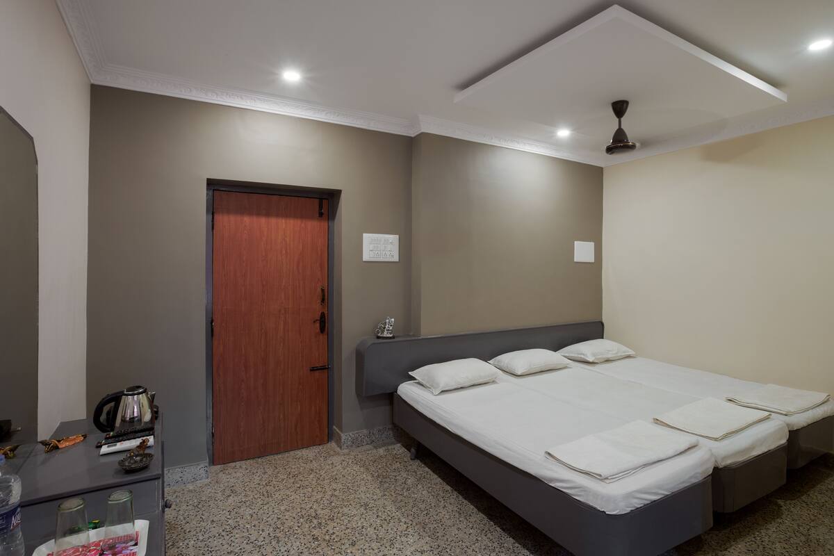 Een hotelkamer met een bed, een bureau met een waterkoker en een deur.