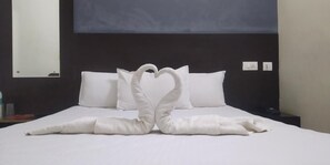 Ein Hotelzimmer mit einem ordentlich bezogenen Bett, einem großen Spiegel und einem dunklen Kopfteil.