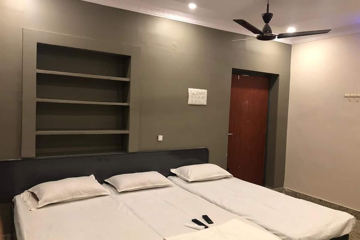 Een slaapkamer met twee enkele bedden, een plafondventilator, een kledingkast en inbouwkasten.