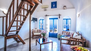 A spacious living room with a wooden staircase, a sofa set, a dining table with fruit, and a view through blue doors.