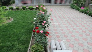 A pathway leading to a building with a gated entrance, surrounded by a well-maintained garden with various plants and flowers. - Hotel Oniks (Kutaisi)