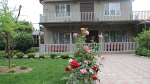 A two-story house with a balcony, surrounded by a garden with roses. - Hotel Oniks (Kutaisi)