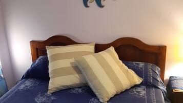 Ein Bett mit blauer Bettdecke, zwei Kissen und einem Holz-Kopfteil.