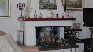 Un salon doté d’une cheminée, d’un téléviseur et de divers objets décoratifs disposés sur la manteau de cheminée.