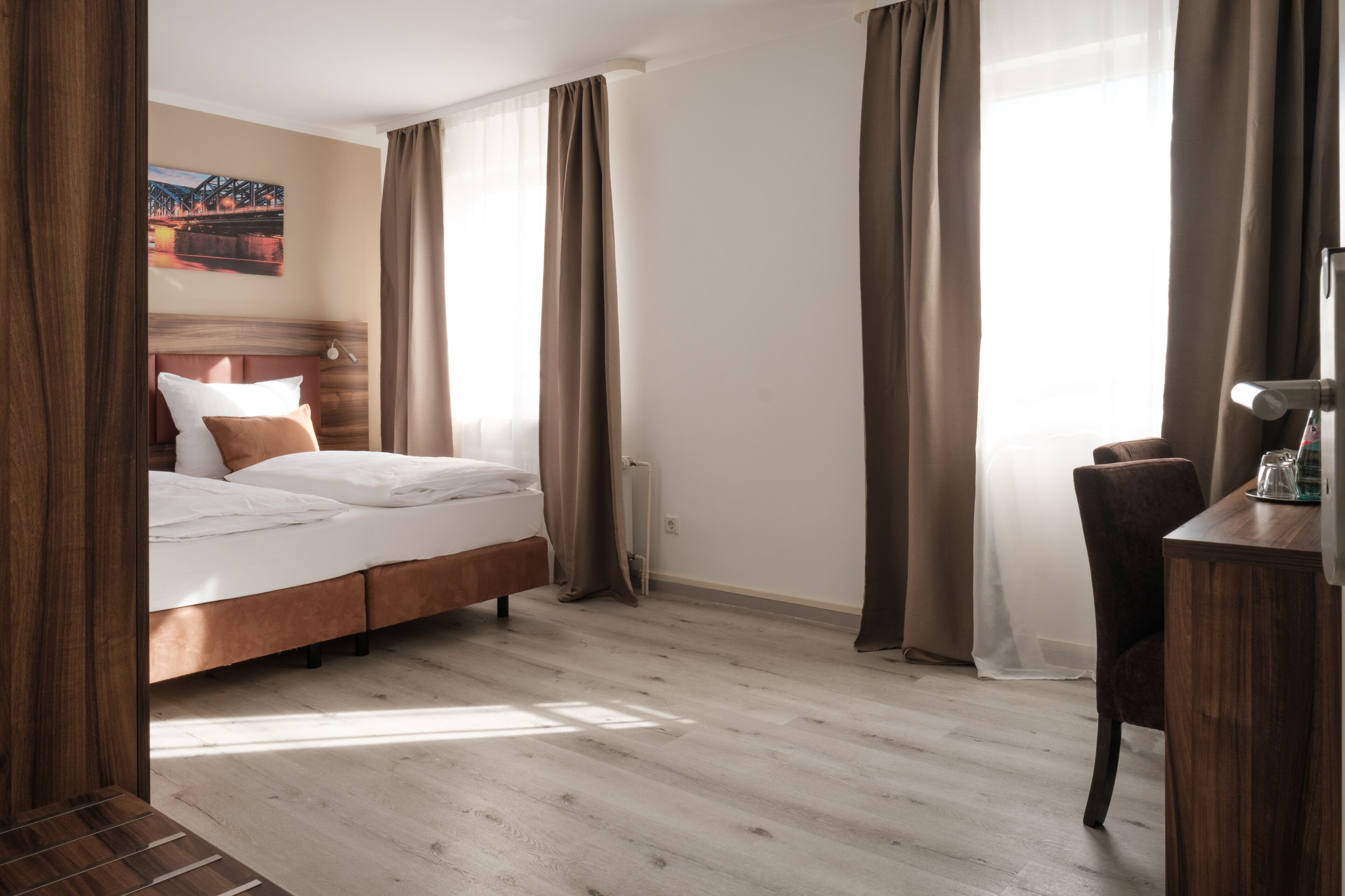 Une chambre d’hôtel avec un lit, un bureau et une fenêtre avec des rideaux.