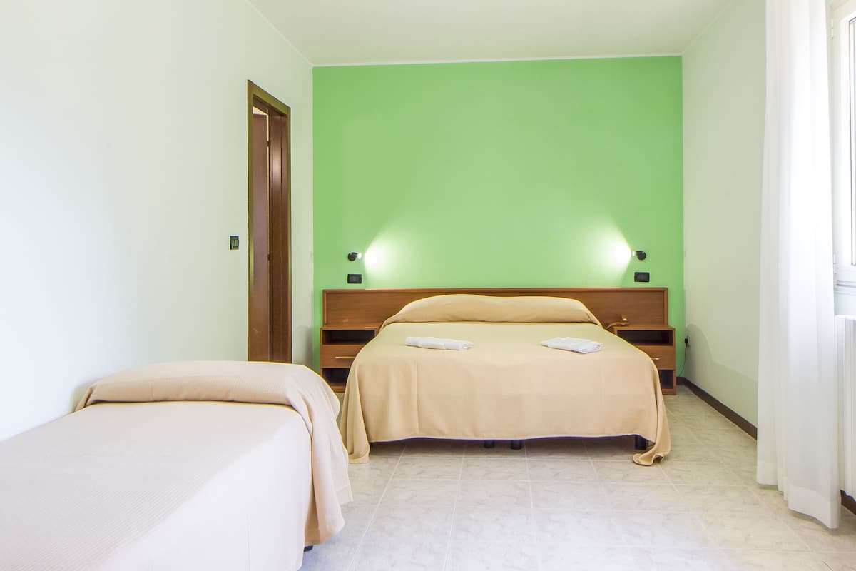 Ein Hotelzimmer mit zwei Betten, einer grünen Wand und einem Holzkopfende.