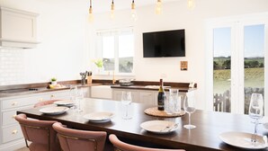A modern kitchen with a large island, pendant lighting, and a view of the countryside. - Northern Hideaways, Sunnyside, Otterburn (Newcastle-upon-Tyne)