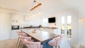 A modern kitchen with a large island, bar stools, and a built-in oven.