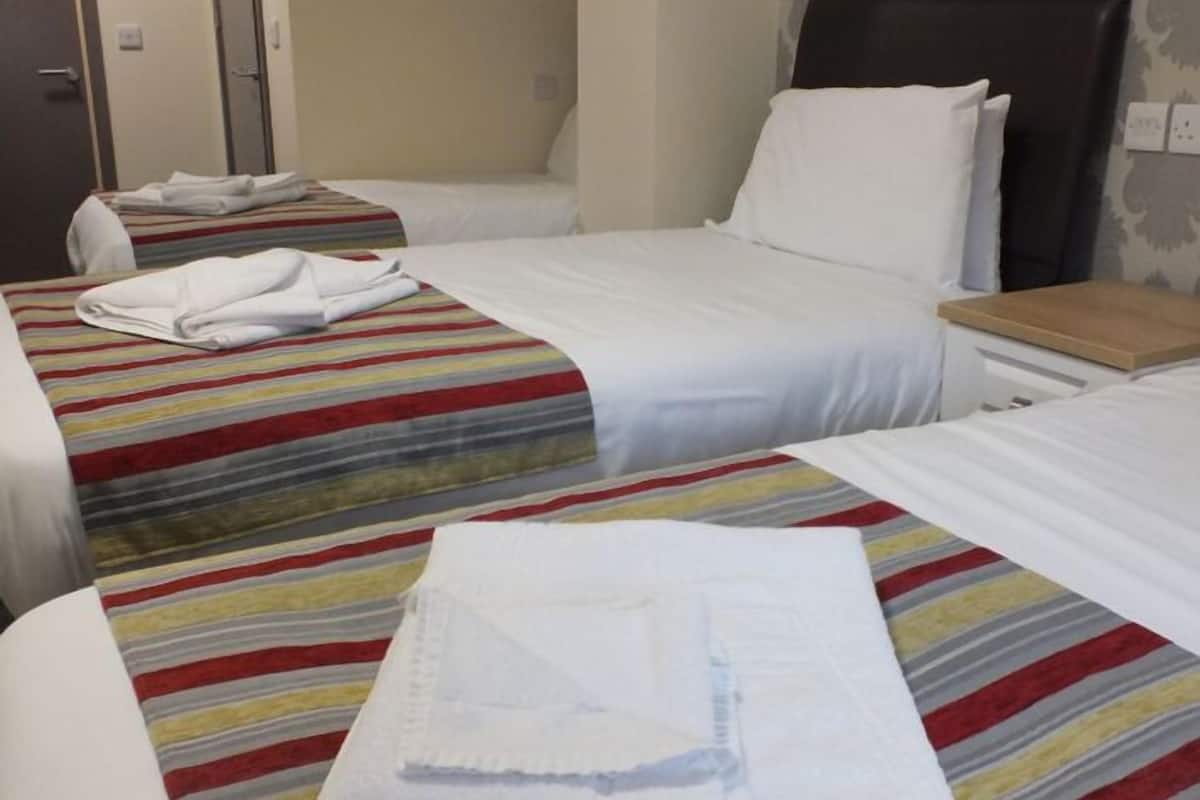A hotel room with two beds, each with a striped bedspread and white pillows.