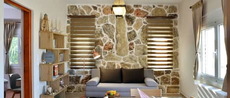 A cozy living room with a stone wall, a sofa, a coffee table, and a bookshelf.