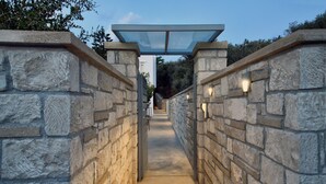 A stone pathway leading to a covered entrance with a glass canopy. - Villa ANVA, amazing views, walk to the beach (Daratsos)