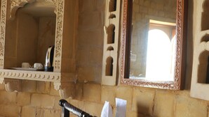 A room with a wooden desk, a chair, a mirror, and a shelf with a teapot and cups. - Himmatgarh Palace (Jaisalmer)