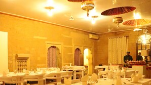A restaurant with multiple tables set for dining, each with white tablecloths and napkins. - Himmatgarh Palace (Jaisalmer)