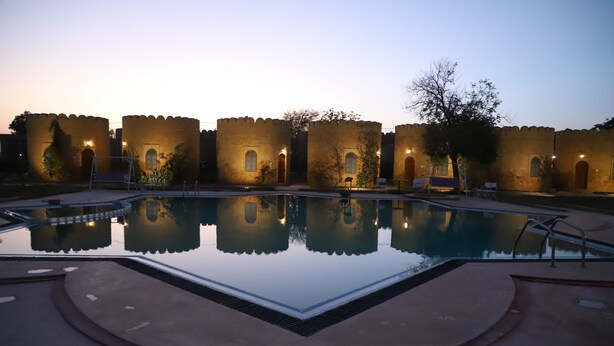 A swimming pool with a clear reflection, surrounded by stone walls and small trees. - Himmatgarh Palace (Jaisalmer)