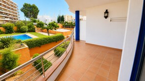 A balcony with a view of a swimming pool, a blue pillar, and a white wall with a light fixture. - Apartament Vip Ancla first line of the sea (Escala, L')