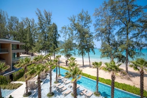 A resort with a pool, palm trees, and a beach view.
