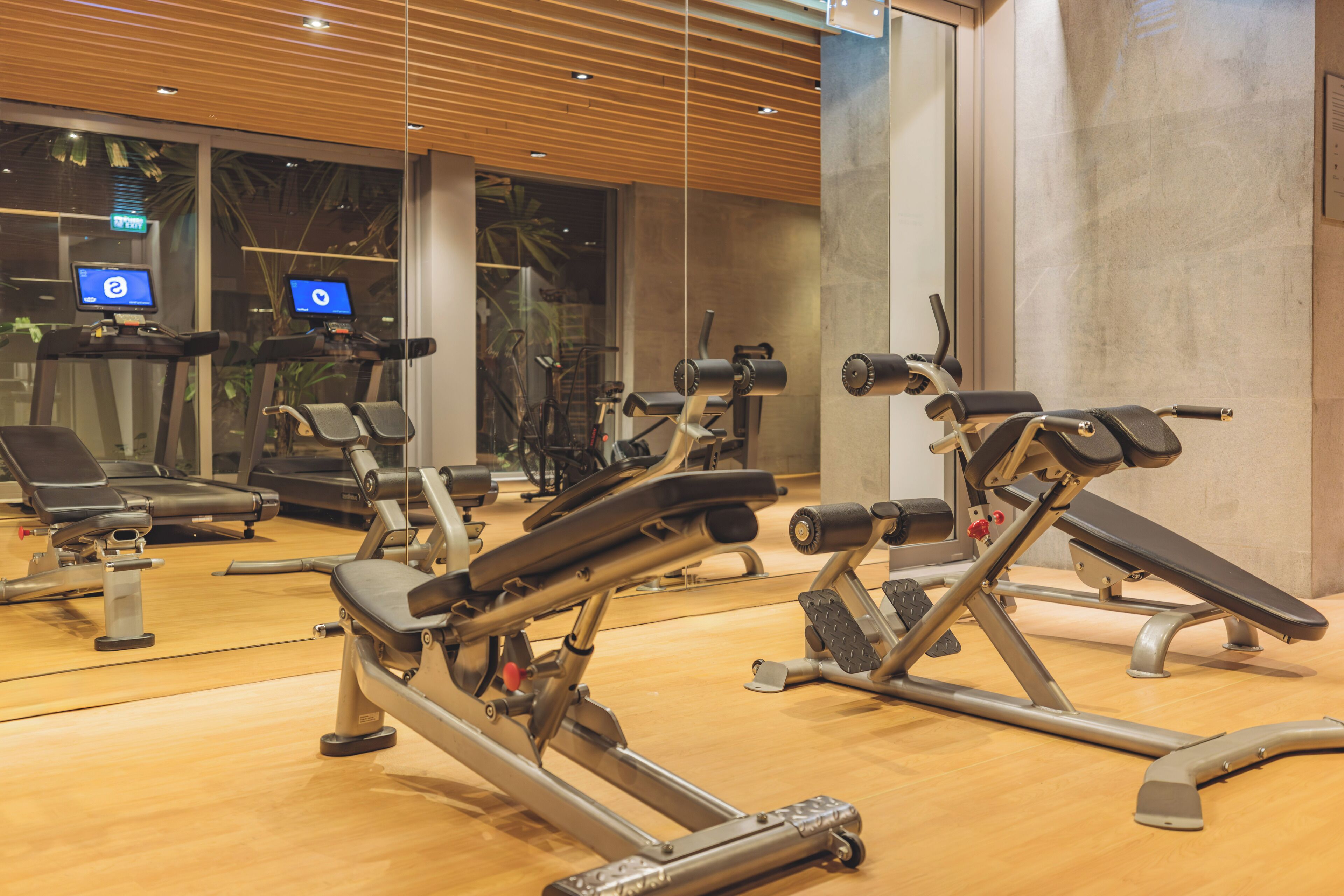 Une salle de sport équipée de divers appareils d’exercice, notamment des tapis de course et des appareils de musculation, et dotée d’un grand miroir qui reflète les équipements.