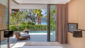 Ein modernes Hotelzimmer mit einem großen Bett, einer Sitzecke und Blick auf einen Pool und Palmen.