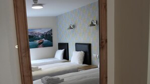Un dormitorio con dos camas, cabecero de madera, mesita de noche y un espejo en la pared.