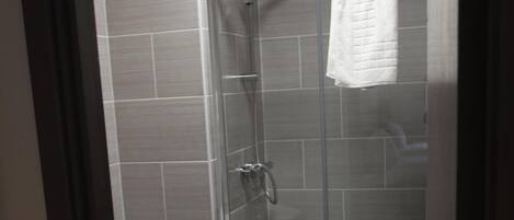 A glass-enclosed shower stall with a white towel hanging on the door.