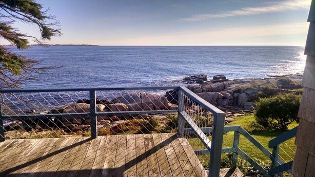 A wooden deck with a metal railing overlooking a rocky coastline and the ocean. - Quintessential Maine waterfront! (Biddeford)