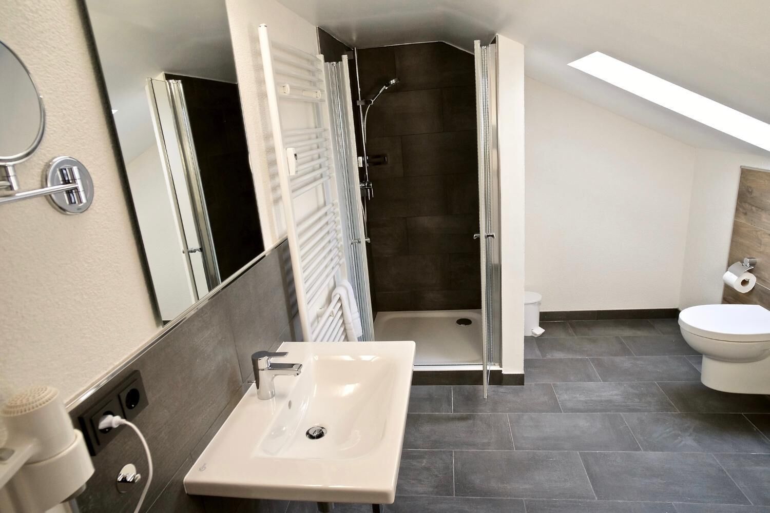 A modern bathroom with a shower, toilet, and sink.