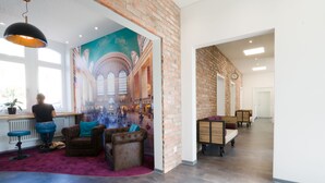A spacious lobby with a mural, leather seating, and a bar area. - Bahnhof ERZINGEN hotel coffee  & more (Klettgau)