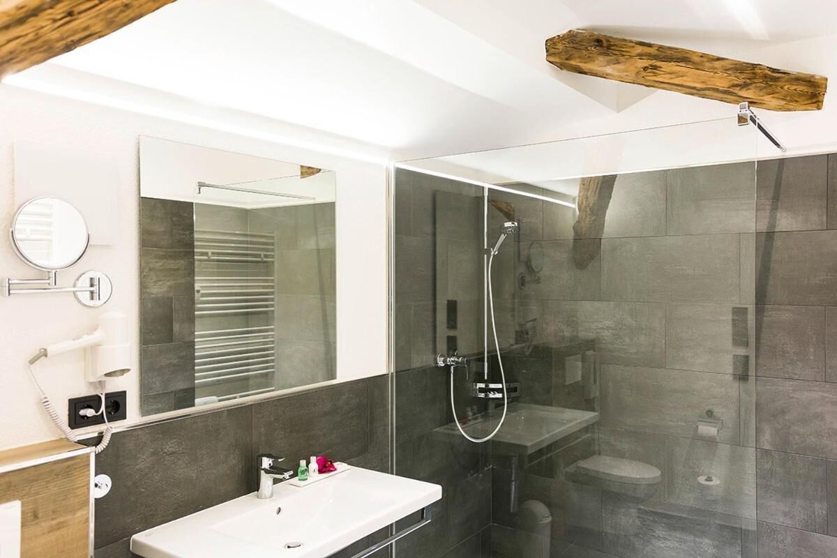 Une salle de bain moderne avec une douche à parois de verre, un lavabo blanc et un grand miroir.