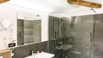 Une salle de bain moderne avec une douche à parois de verre, un lavabo blanc et un grand miroir.