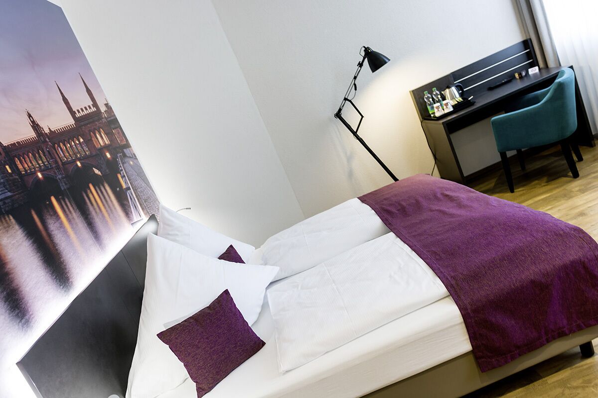 Une chambre d’hôtel avec un lit, un bureau et une chaise.