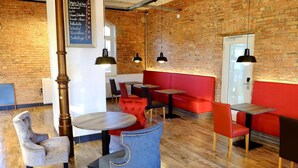 A restaurant interior with brick walls, wooden floors, and red and black seating. Tables and chairs are arranged for dining. - Bahnhof ERZINGEN hotel coffee  & more (Klettgau)