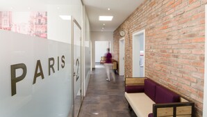 A modern interior with a brick wall, a bench, and a glass wall with the word "PARIS" on it. - Bahnhof ERZINGEN hotel coffee  & more (Klettgau)